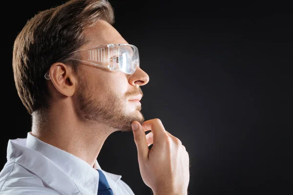 Científico experto pensativo mirando a un lado tocándose la barbilla . — Foto de Stock