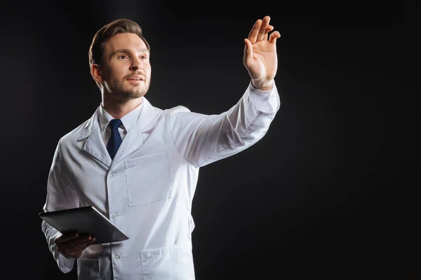 Улыбка квалифицированного медика, поднимающего руку и держащего планшет . — стоковое фото