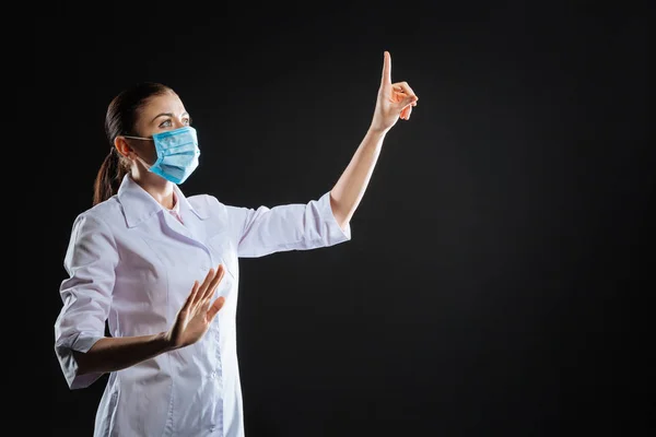 Enfermera ocupada atenta mirando hacia arriba tocando la pantalla táctil invisible . — Foto de Stock