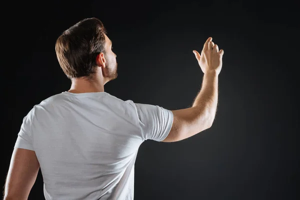 Focado homem inabalável olhando para o lado levantando a mão . — Fotografia de Stock