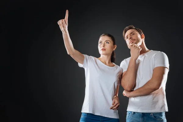 Interested cute woman standing and pointing up. — Stock Photo, Image