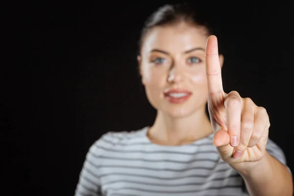 Zufriedene süße Frau lächelt und zeigt einen Finger. — Stockfoto