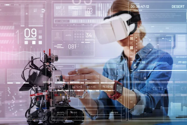 Engenheiro cuidadoso tocando um robô enquanto está em óculos de realidade virtual — Fotografia de Stock