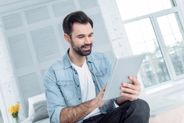 Homem barbudo alegre usando seu tablet — Fotografia de Stock