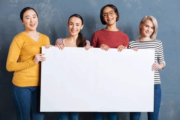 Groep positieve vrolijke vrouwen die houden van een poster — Stockfoto