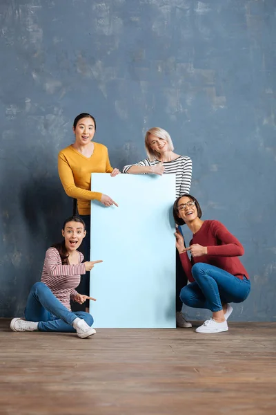 Radostnou pozitivní ženy stojící kolem plakátu — Stock fotografie