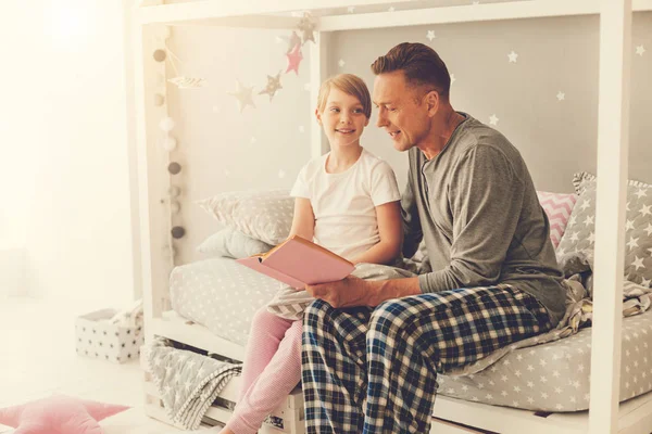 Красивый милый мужчина, читающий книгу своей дочери. — стоковое фото