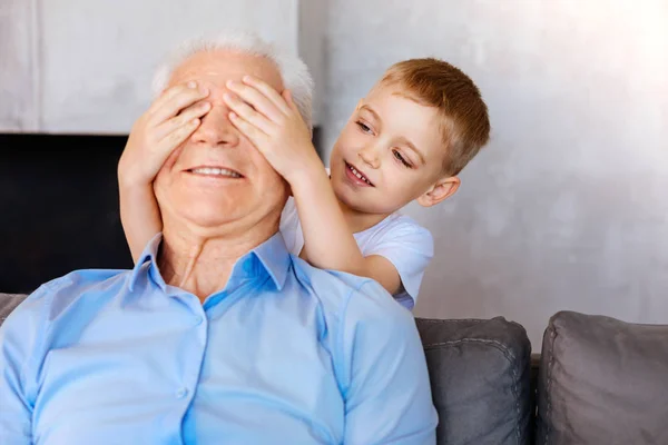 Angenehmer netter Junge sitzt hinter seinem Großvater — Stockfoto