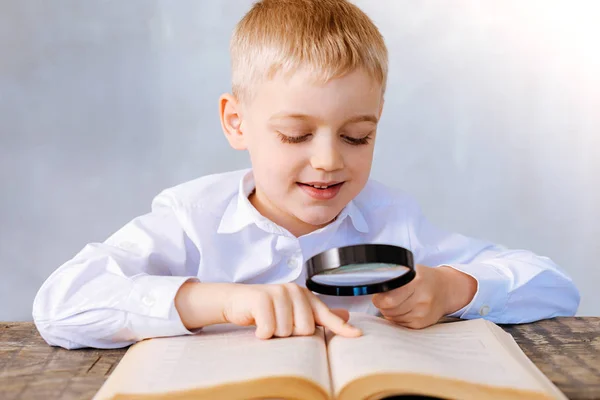 Positive cute boy holding magnifying glass — Stock Photo, Image