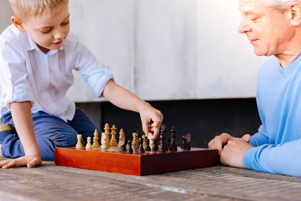 Joyful söt pojke håller en schackpjäs — Stockfoto