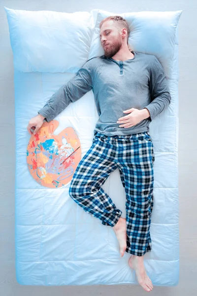Homem sonolento segurando paleta na mão direita — Fotografia de Stock