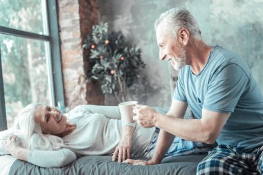 Oturma ve bir fincan tutan hoş özenli adam.