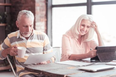 Bir fincan tutarak ve belgeyi okuyan ciddi meşgul adam.
