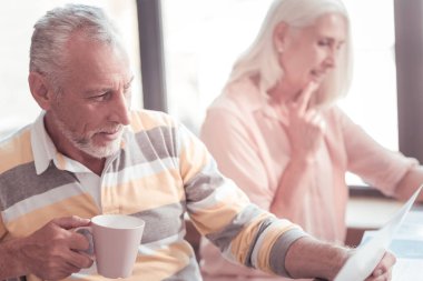 Oturma ve belgeyi okuyan düşünceli yaşlı adam.