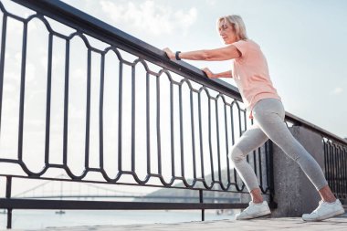 Korkuluk üzerine güvenerek ısınma düşünceli atletik kadın.