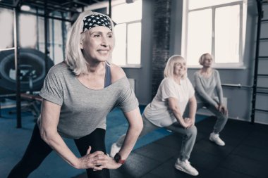 Üç yaşlı kadın spor salonunda lunges yapıyor