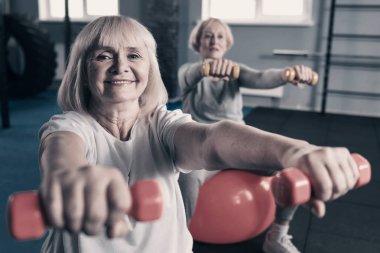 Yaşlı kadın spor salonunda dumbbells ile egzersiz