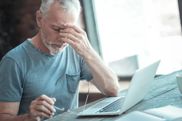 Hombre serio e inquebrantable sentado y sintiendo la cama él mismo . — Foto de Stock