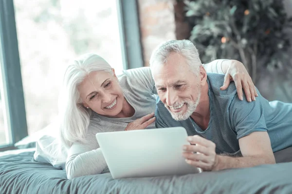 Joyful casal bonito deitado na cama e sorrindo . — Fotografia de Stock