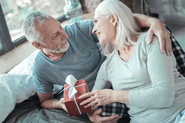 Charmant couple de personnes âgées couché et tenant le présent . — Photo