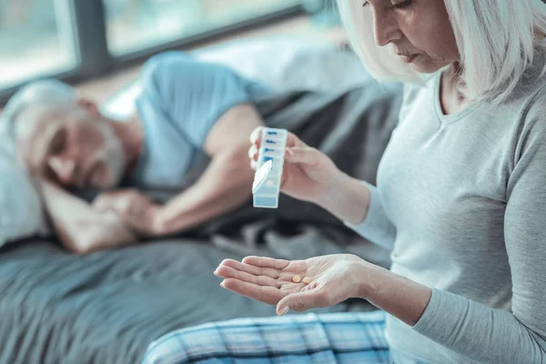 Concentrato donna premurosa seduta e in possesso di pillole . — Foto Stock