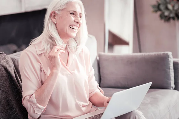 Mujer alegre y agradable sentada en el sofá y sonriendo . — Foto de Stock