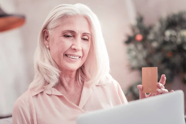 Mulher satisfeita interessada olhando para a tela segurando cartão de crédito . — Fotografia de Stock