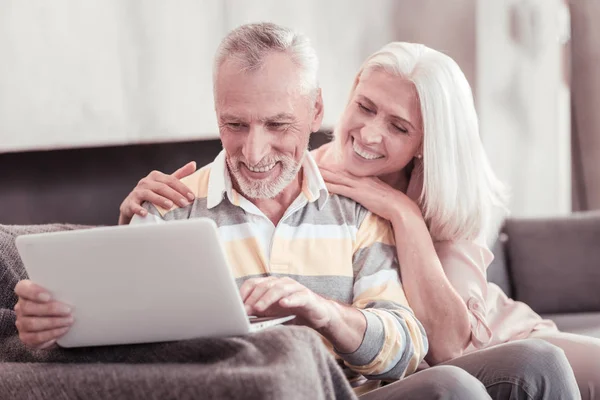 Gülümseyen ve laptop ile çalışma baktılar yaşlı çift. — Stok fotoğraf