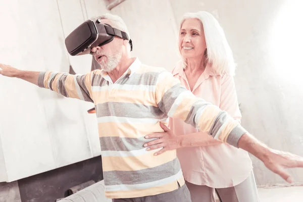 Hombre interesado de pie y mirando a través de las gafas VR . — Foto de Stock