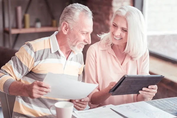 Betagtes Ehepaar sitzt und bedient sich des Tablets. — Stockfoto