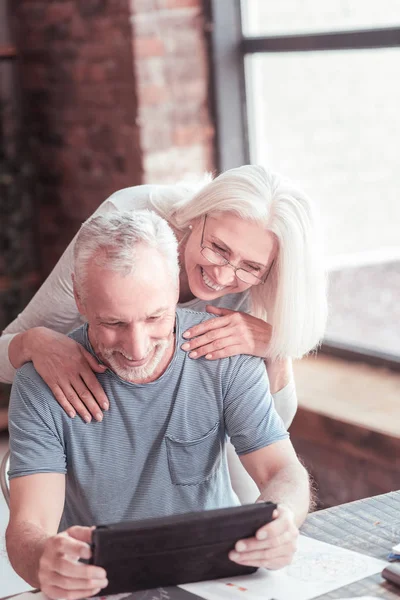 Pretty senior lady tilting to her husband and smiling. — Stock Photo, Image