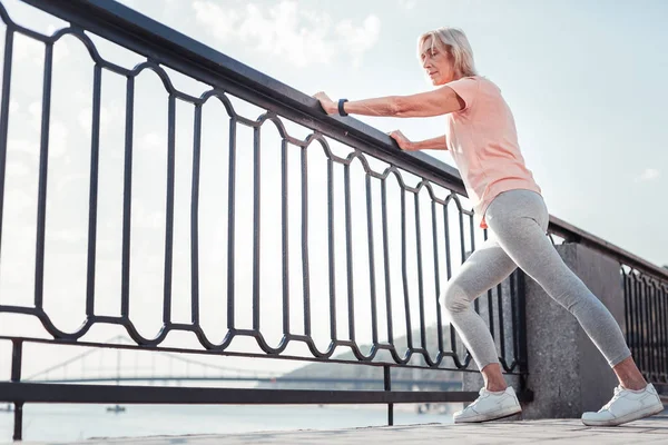 Thoughtful athletic woman warming up relying on the railing. — Stock Photo, Image