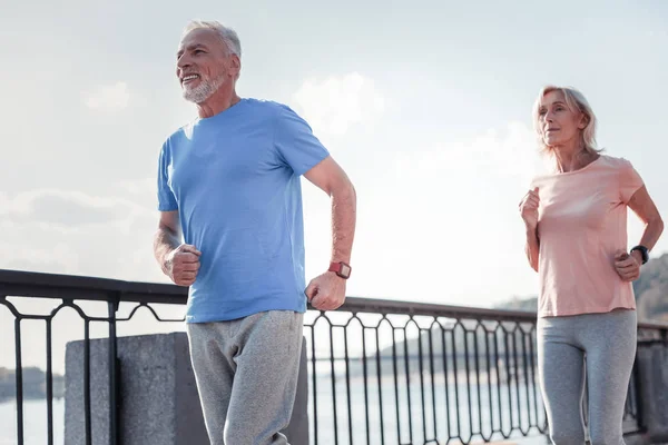 Pleasant handsome man smiling and running. — Stock Photo, Image