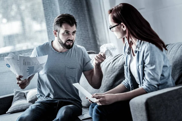 Enojado hombre estresante sosteniendo papeles y mirando a la mujer . — Foto de Stock