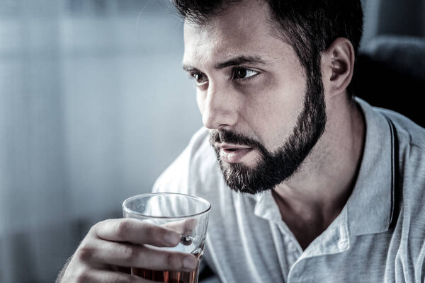 Thoughtful concentrated man looking aside and drinking.