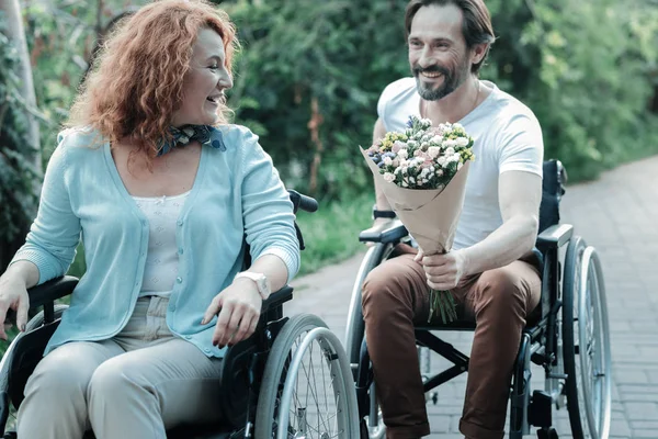 Glad brunett presentera blommor till sin kvinna — Stockfoto