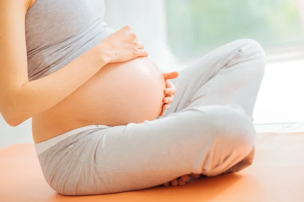 Careful impregnate woman touching to her stomach and mediating. — Stock Photo, Image