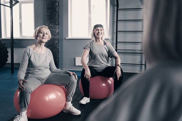 Бодрые пожилые женщины слушают инструкцию своего тренера
