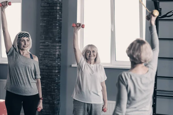 Energisk kvinnor upprepande hantlar träning efter sina tränare — Stockfoto