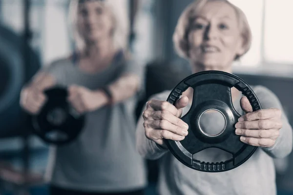 Nahaufnahme der Gewichtsscheibe in den Händen der Seniorin — Stockfoto