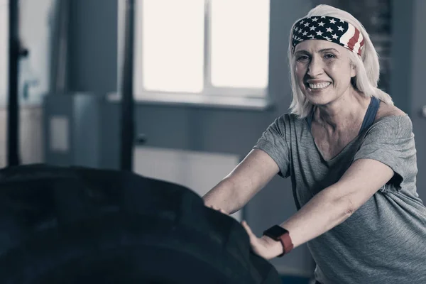 Encantadora mujer mayor empujando un neumático grande — Foto de Stock