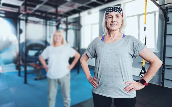 Smiling woman standing with hands on hips at gym
