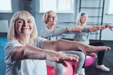 Neşeli yaşlı kadın fitness kulübünde eller germe