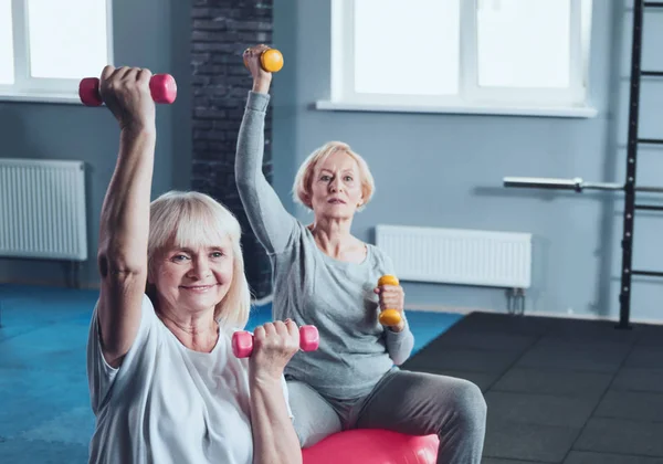 Due signore anziane che sollevano pesi durante l'allenamento in palestra — Foto Stock