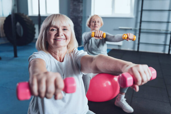 Positive minded senior lady enjoying workout at fitness club