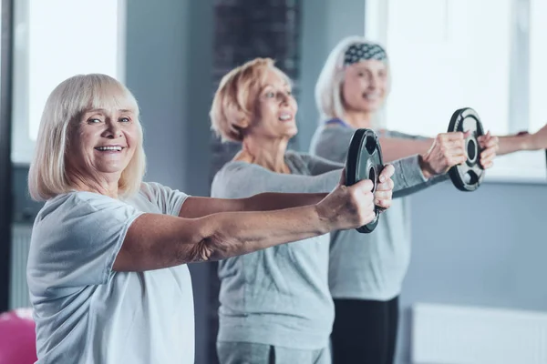 Focus selettivo sulla donna anziana sorridente che tiene il disco del peso — Foto Stock