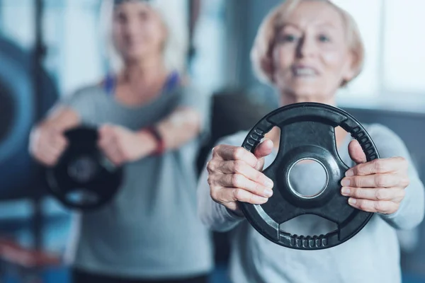 Sporty aposentado senhora segurando disco de peso no clube de fitness — Fotografia de Stock