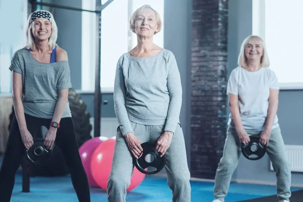 Actieve rijpe vrouwen swingende gewicht schijf op sportschool — Stockfoto