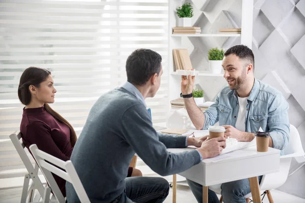 Hombre feliz sentado con sus colegas en la mesa — Foto de Stock