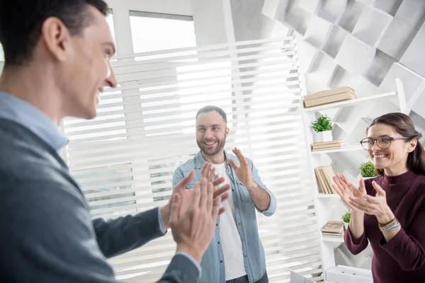 Felices colegas de pie en la oficina y aplaudiendo — Foto de Stock